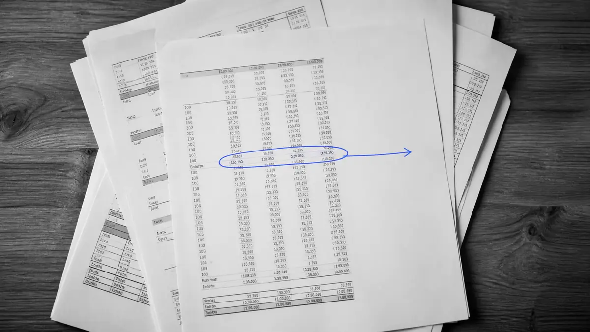 Liasse de documents comptables avec une ligne entourée à la main et une flèche vers la marge vide, illustration de ce que le bilan ne dit pas sur la rentabilité.